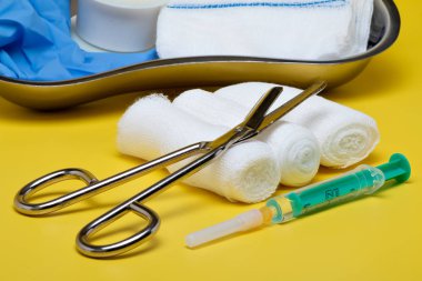 Sıva ve bandaj makas ve sarı bir arka plan üzerinde şırınga ile