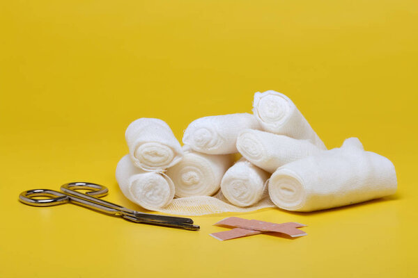 Пластыри и бинты с ножницами и шприцами на желтом фоне
