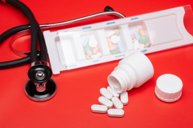 Blister, stetoskop, kırmızı bir arka plan ile izole tablet