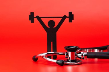 Kırmızı arka plan ile izole ağırlık kaldırma piktogram, stetoskop, yakın çekim