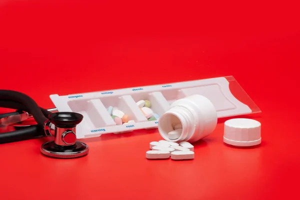 Blister Comprimidos Isolados Com Estetoscópio Sobre Fundo Vermelho — Fotografia de Stock