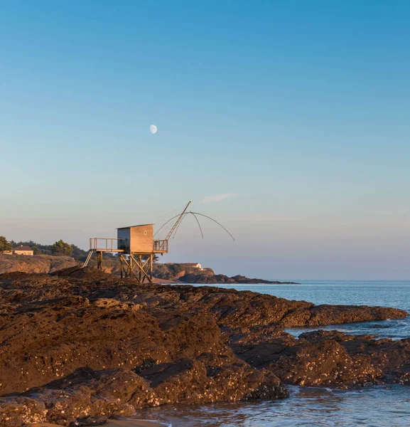 Okyanusun mesafe moon ile batımında Hut'ta Balık tutma