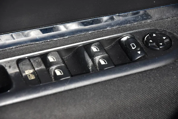 closeup of a door control panel in a modern car. Arm rest with window control panel, door lock button, and mirror control in used car.