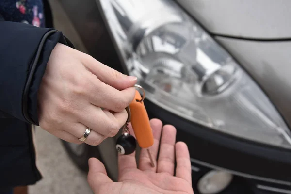 car sales. one person sells car and gives the key to the new owner - Image