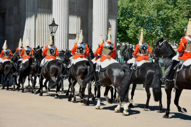 Royal guards on horseback dressed in ceremonial red coats pass i clipart