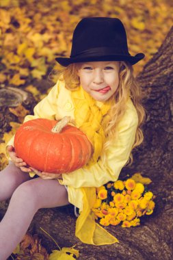 Sonbahar arka planda büyük kabak ile küçük güzel sarışın kız