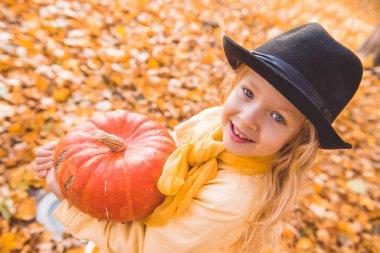 Sonbahar arka planda büyük kabak ile küçük güzel sarışın kız
