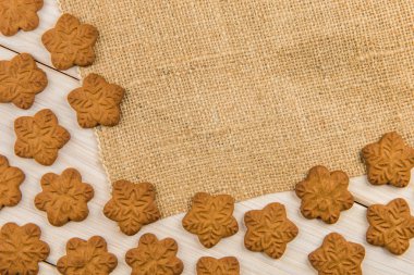 Noel ve yeni yıl gingerbread çerezleri kahverengi çuval arka plan dokusu üzerinde çerçeveli kar taneleri ile.