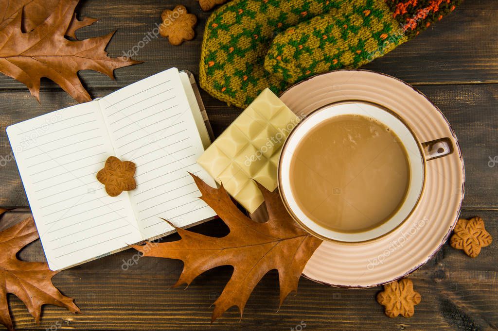 Cup of hot coffee White chocolate cookies with oak leaves with mitten notebook on wooden background