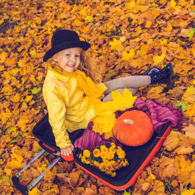 Küçük sarışın kız ve sonbahar arka planda büyük kabak.