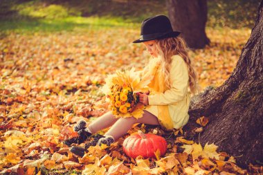Küçük sarışın kız ve sonbahar arka planda büyük kabak.
