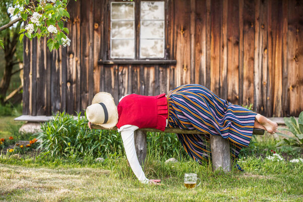 Glass of beer and woman sleeping on a bench, Ligo