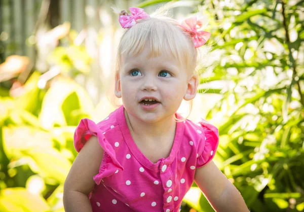 Vacker glad liten baby flicka på en grön ljusa sommar-bakgrund — Stockfoto