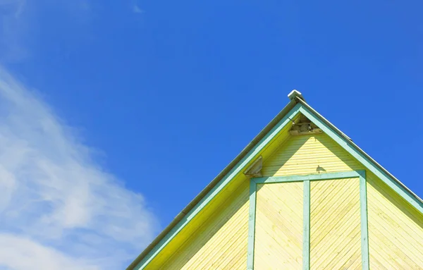 一座质朴的黄色木制建筑的顶部碎片 燕子窝在屋顶下 靠着乌云在蓝天下筑巢 复制空间 选择性焦点 免版税图库图片