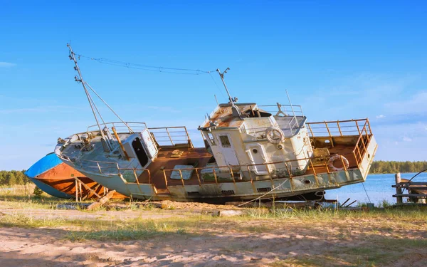 Eski terk edilmiş paslı balıkçılık ayakta kumlu nehir kıyısındaki bir güneşli yaz gününde gemi. Kavramsal peyzaj, seçici odak. Karelya, Rusya Cumhuriyeti.