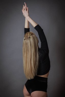 Siyah iç çamaşırlı, uzun sarı saçlı, sırtı dönük ince bir kız.