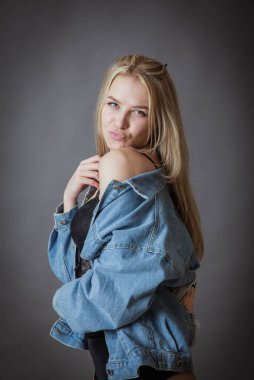 Sarışın güzel siyah iç çamaşırlarıyla poz veriyor ve siyah arka planda kot pantolon var.