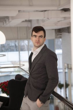 Parlak, modern bir ofiste iş elbisesi içinde dizüstü bilgisayarla çalışan bir iş adamı.