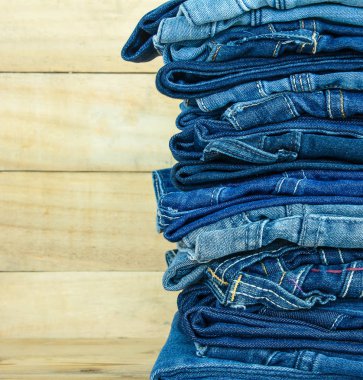 Ahşap arka planda üst üste dizilmiş kot pantolon