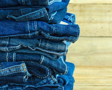  jeans stacked on wooden floor. blank background for design