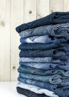  jeans stacked on wooden floor. blank background for design