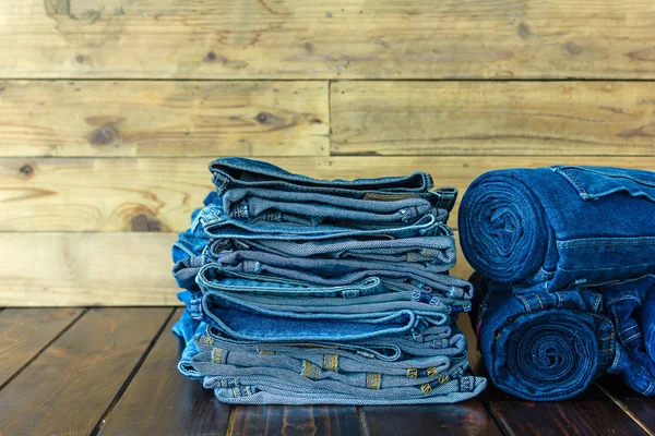 Jeans apilados sobre un fondo de madera — Foto de Stock