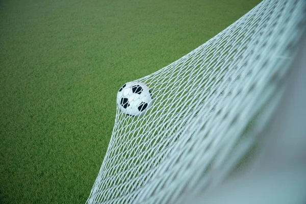 3D rendering fotboll bollen i mål. Fotboll i nät med spotlight och stadion ljus bakgrund, framgångskoncept. Fotboll med grönt gräs — Stockfoto