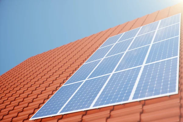 3D ilustrace solární panely na červené střeše domu. Solární panely s odrazem nádherné modré oblohy. Koncept obnovitelné energie. Ekologická, čistá energie. Zelená energie. Fotovoltaické solární buňky — Stock fotografie