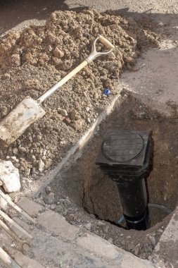 Yeni bir su sayacı yolun ortasında yükleme. İngiltere'de. Yerdeki bir deliğe yer alan yeni siyah plastik gövde.