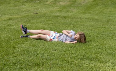 Child playing at rolling down a grassy hillside clipart