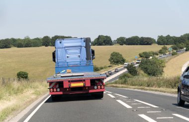 Wiltshire, İngiltere'de İngiltere'de de A303 yol arkadan gördüm flatbed kamyon. Boş bir araç bir meşgul tek lane anayol üzerinde seyahat.