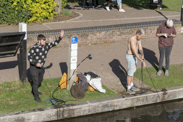 Young man throwing a neodymium magnet into the Kennet and Avon Canal at Newbury, Berkshire, England UK