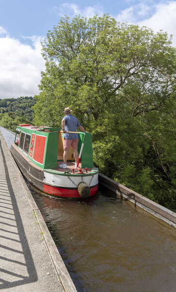 Pontcysyllte Aqueduct, Trevor, North Wales, UK. 2018.  Narrowboat with man on the tiller passing over the aqueduct.