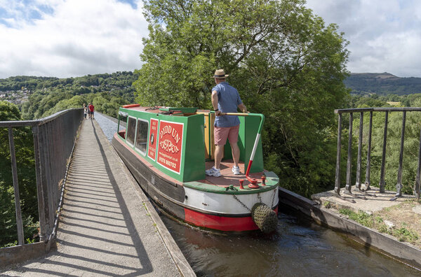 Pontcysyllte Aqueduct over the River Dee at Trevor near Llangollen North East Wales. Man on the tiller of a narrowboat navigating the narrow aqueduct