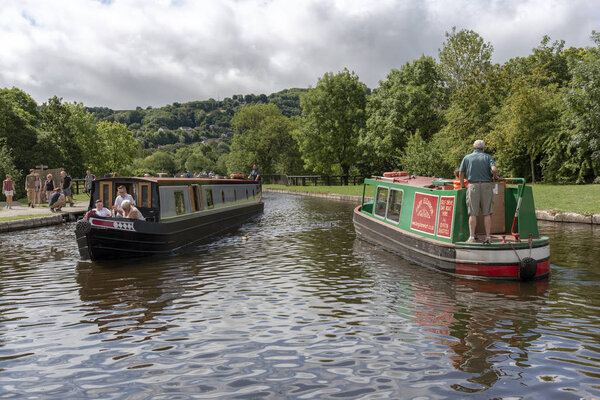 A narrowboat exiting alongside another entering  the Pontcysyllte Aqueduct over the River Dee at Trevor Basin near Llangollen North East Wales. 