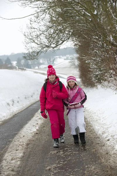 Children walking to school along a snow covered road in Hampshire, England, UK