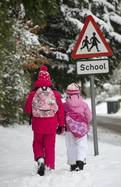 Children walking to school along a snow covered road in Hampshire, England, UK