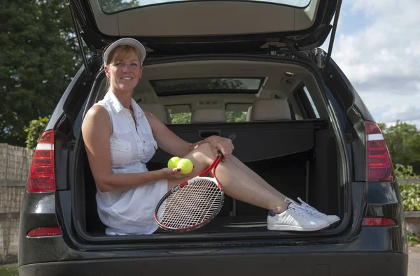Woman in tennis outfit sitting in car