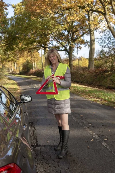 Vrouwelijke Automobilist Het Blussen Van Een Reflecterende Veiligheid Driehoek Een — Stockfoto