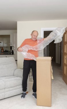 Man unpacking a brown cardboard box containing an excessive amount of protective air bags clipart