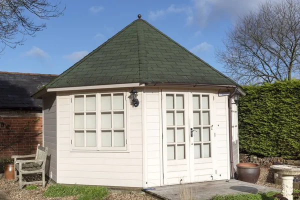 A pine constructed garden office with decking area and landscaped garden, viewed in winter. Situated in Southern England UK