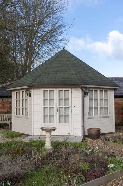 A pine constructed garden office with decking area and landscaped garden, viewed in winter. Situated in Southern England UK