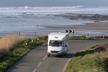 Widemouth Bay, Cornwall, İngiltere, İngiltere'de. Şubat 2019. Widemouth Bay, Bude, Kuzey Cornwall düşük tide denizde bir fon ile yakın. Sahil yolu üzerinde bir kamyonet ve karavan.