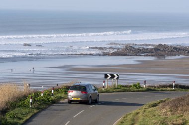 Widemouth Bay, Cornwall, İngiltere, İngiltere'de. Şubat 2019. Widemouth Bay, Bude, Kuzey Cornwall düşük tide denizde bir fon ile yakın. Sahil yolu üzerinde küçük araba