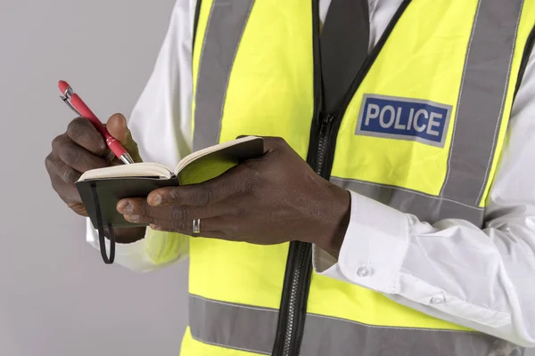 A British police officer making notes into a black notebook