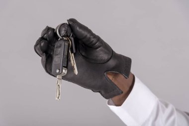 İngiltere, Birleşik Krallık. Mayıs 2019. Adamın eli, ateşleme anahtarlarını tutan siyah deri eldiven giyiyor.,