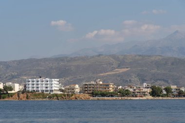 Chania, Girit, Yunanistan. Haziran 2019. Hanya Kuzey Girit kıyı manzara dağlar bir zemin ile otel ve evler gösteren