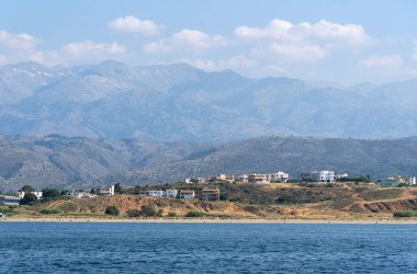 Chania, Girit, Yunanistan. Haziran 2019. Hanya Kuzey Girit kıyı manzara dağlar bir zemin ile otel ve evler gösteren