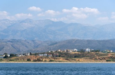Chania, Girit, Yunanistan. Haziran 2019. Hanya Kuzey Girit kıyı manzara dağlar bir zemin ile otel ve evler gösteren
