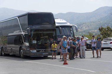 Lassithi, Girit, Yunanistan. Haziran 2019. Tur rehberi ve turistler bir grup. Lassithi Plato bir arka plan ile Park otobüsler ve ziyaretçiler araba büyüyen üretmek için verimli bir alan.